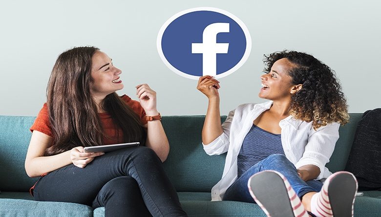 Artigram Woman holding Facebook emoticons on a couch Young women showing a Facebook icon